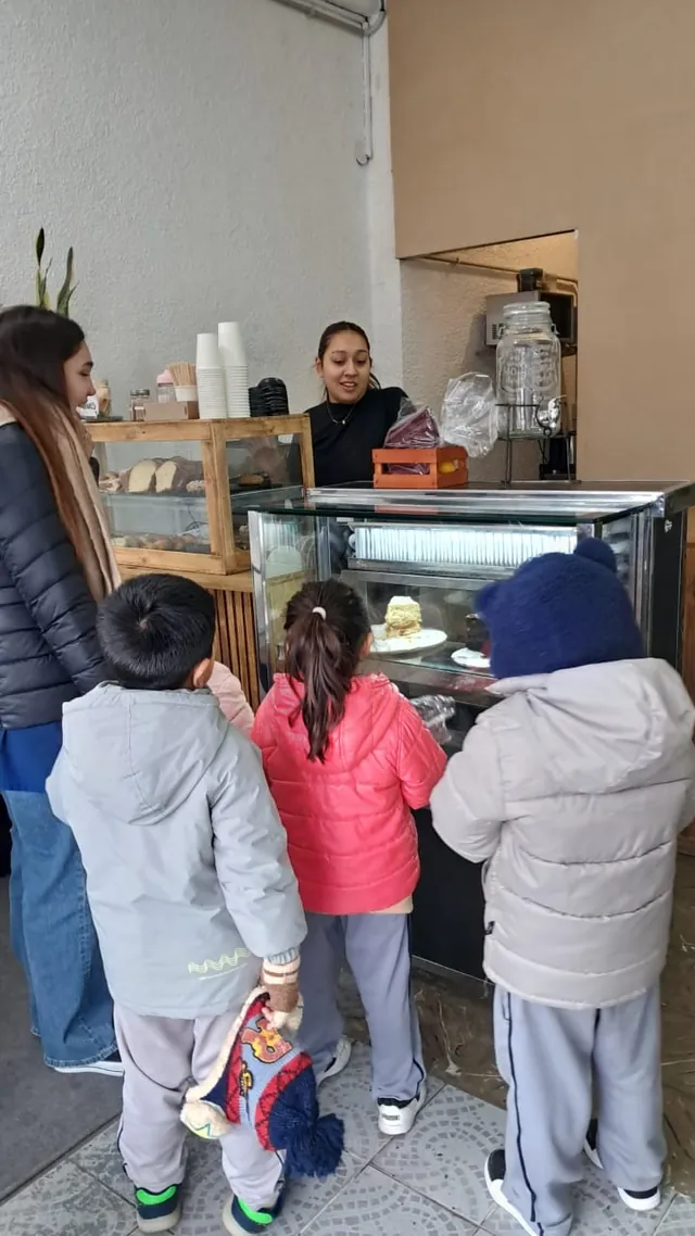 Tres alumnos del Nivel Inicial mirando la vitrina de una panadería