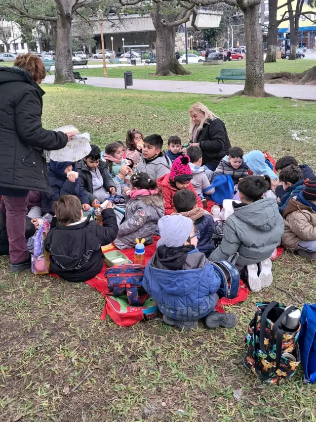 Alumnos del Nivel Inicial haciendo un picnic sobre mantas en una plaza